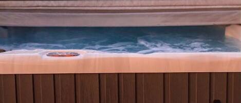A hot tub with a wooden deck in front.