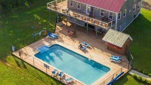 Uma casa de dois andares com uma varanda grande e piscina.
