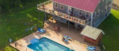 A two-story house with a large deck and a swimming pool.