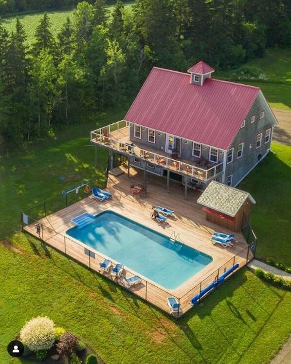 A two-story house with a large deck and a swimming pool.