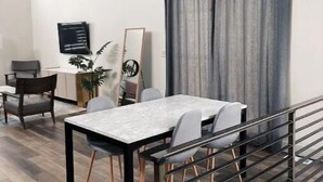 Zona pranzo moderna con tavolo in marmo, sedie bianche e tenda grigia.