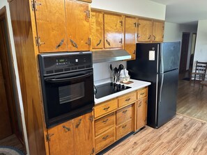 Una cucina con mobili in legno, un piano cottura nero, un lavello e un frigorifero.
