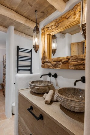 Relax in this serene bathroom with a large mirror, stone basin sinks, and a wooden countertop.