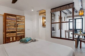 Relax in this stylish room with a large bed, a wardrobe, and a dining area with a table and chairs.