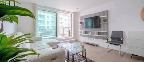 A modern living room with a sofa, coffee table, and a TV mounted on the wall.
