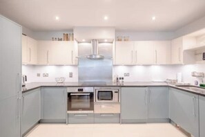 Una cocina moderna con armarios grises, electrodomésticos de acero inoxidable y una isla central.