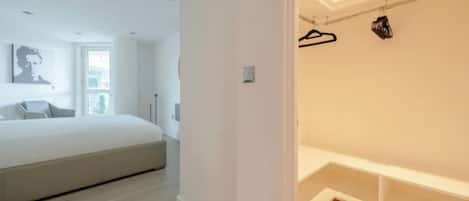 Une chambre à coucher avec un lit, une fenêtre et une armoire où sont suspendus des vêtements.
