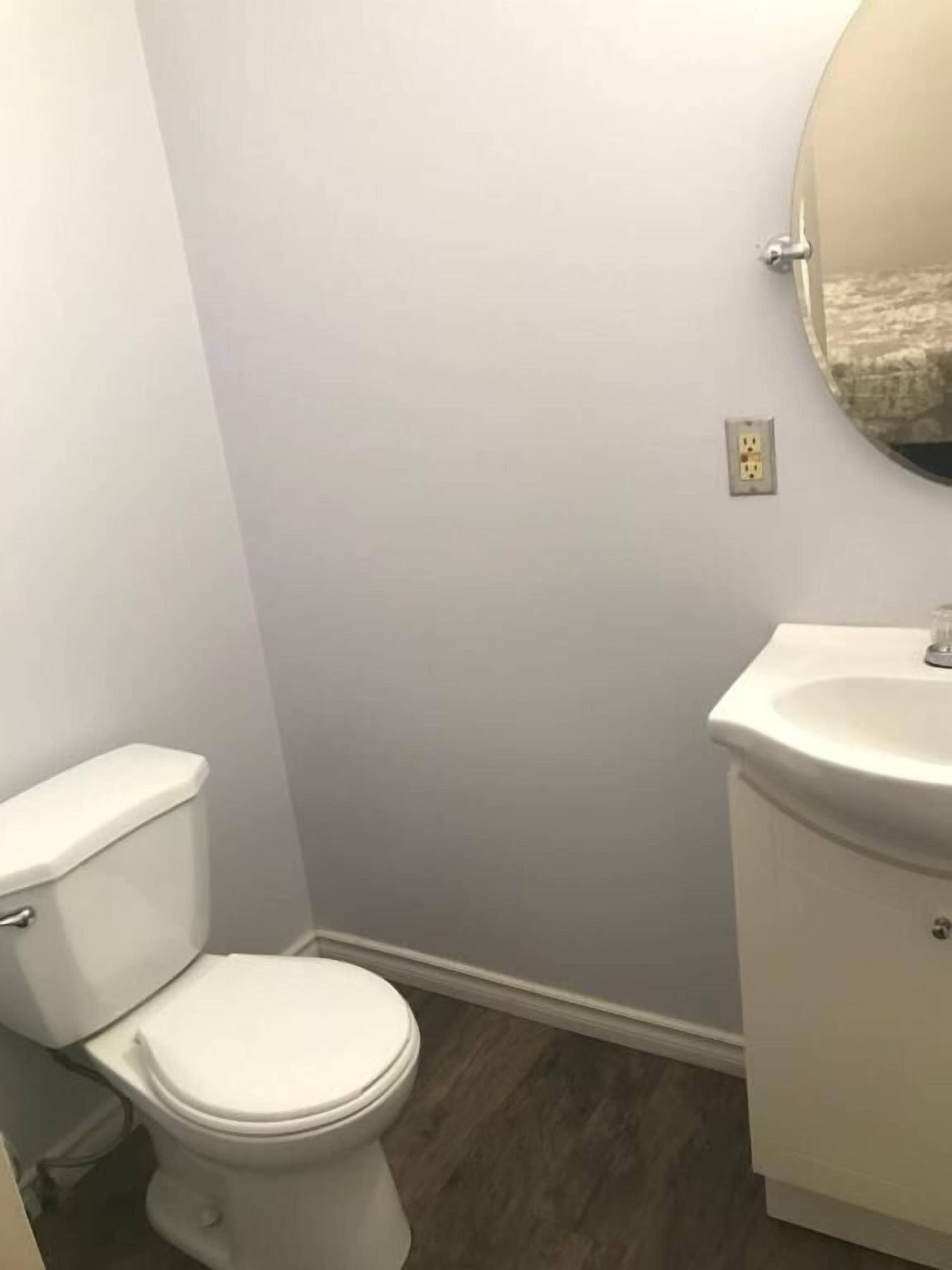 Une salle de bain avec des toilettes, un lavabo et un miroir.
