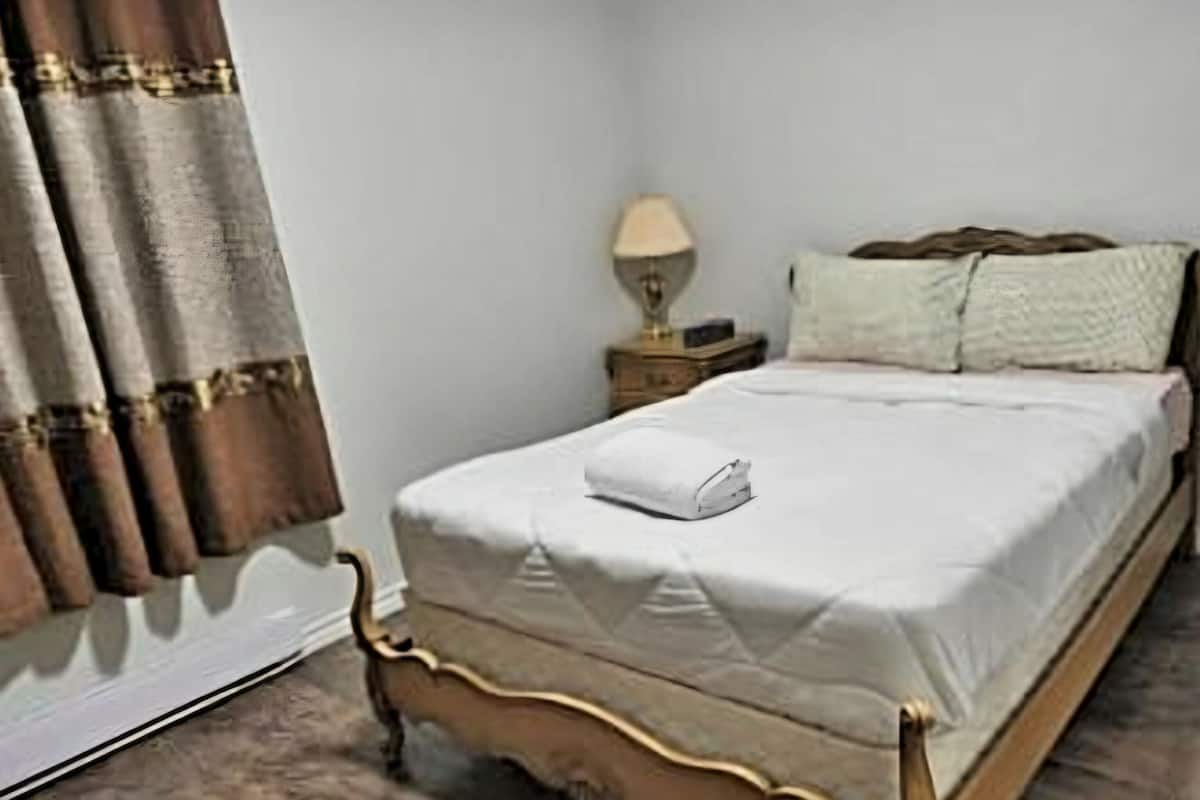 A single bed with a white duvet, a wooden headboard, and a bedside table with a lamp.