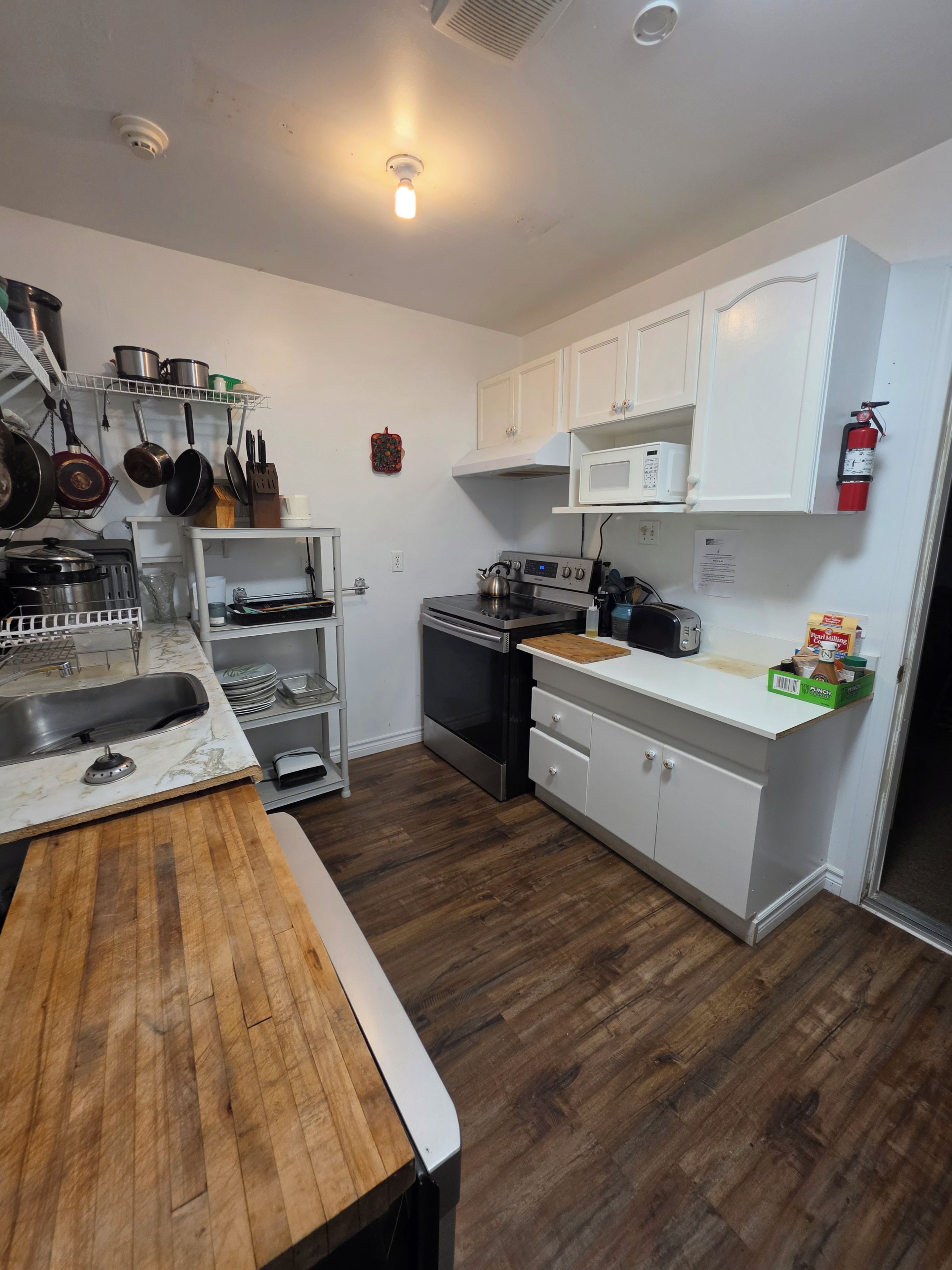 A modern kitchen with white cabinets, stainless steel appliances, and a wooden countertop.
