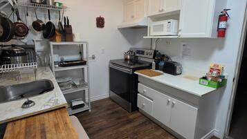 A modern kitchen with white cabinets, stainless steel appliances, and a wooden countertop.