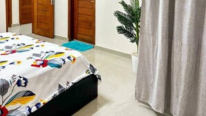 A bedroom with a bed, two wooden doors, a potted plant, and a grey curtain. - Cozy Room In Cotonou City
 (Cotonou)