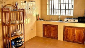 A kitchen with a wooden shelf, tiled walls, a window, and a stove. - Cozy Room In Cotonou City
 (Cotonou)