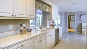 A kitchen with white cabinets, a sink, and a coffee station. - Tropical Family Pool Home Near Siesta Key Beach | Sleeps 9 Dog Friendly,( Check restrictions)| Gulf Gate Sarasota | Sleeps 9 (Sarasota)