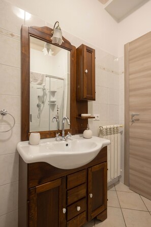 A bathroom with a wooden vanity, a large mirror, a white sink, and a towel rack.