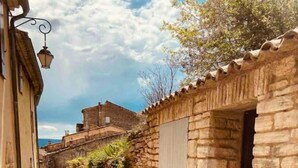 A narrow cobblestone street flanked by stone buildings with a stone wall on one side and a wooden door on the other. - Gordes Idyllique Avec vue Panoramique (Gordes)