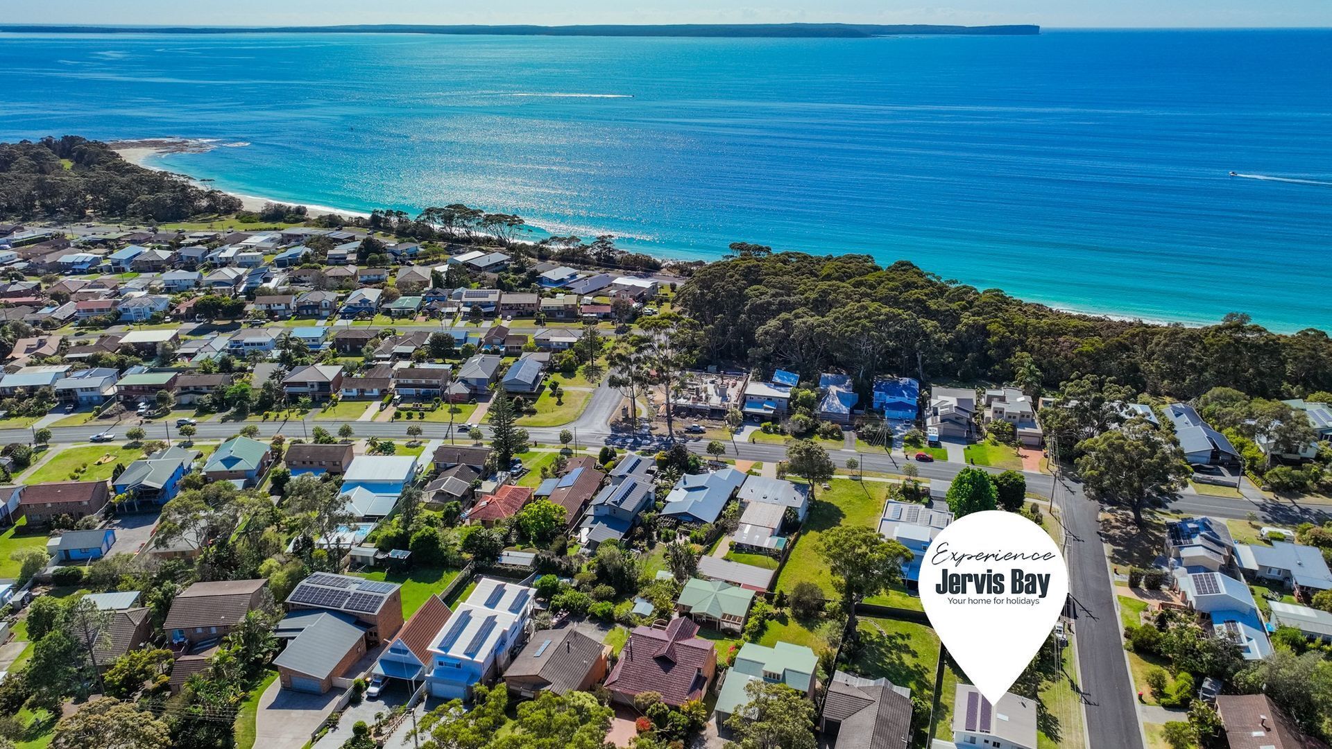 An aerial view of a residential area with houses, roads, and a beach.