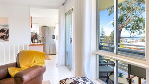 Eine moderne Küche mit Edelstahlgeräten, ein Essbereich mit Tisch und Stühlen und ein großes Fenster mit Blick ins Freie.