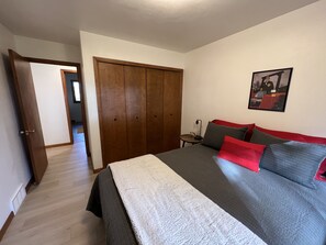 Une chambre à coucher avec un lit, une armoire, une table de chevet et un tableau encadré au mur.