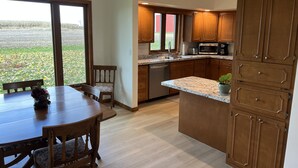 A modern kitchen with wooden cabinets, a granite countertop, and a dining area with a table and chairs.