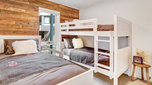 A room with bunk beds, a window with a view, and a small wooden stool with a picture frame.