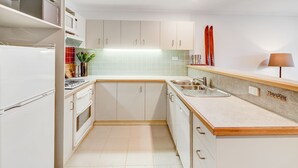 A compact kitchen with white cabinets, a built-in stove, a sink, and a countertop.