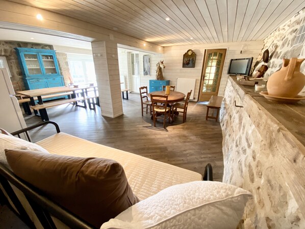 A cozy room with a bed, a dining area with a table and chairs, and a kitchen area with a counter and decorative items. - Ferme Cosy 15p sur la Montagne Ardéchoise, Salle de Réception (Mazan-l'Abbaye)