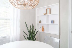 A dining area with a round table, chairs, a hanging light fixture, and a white shelving unit with decorative items. - 3x Properties - Pet Friendly Historic Estate (Lakeland)
