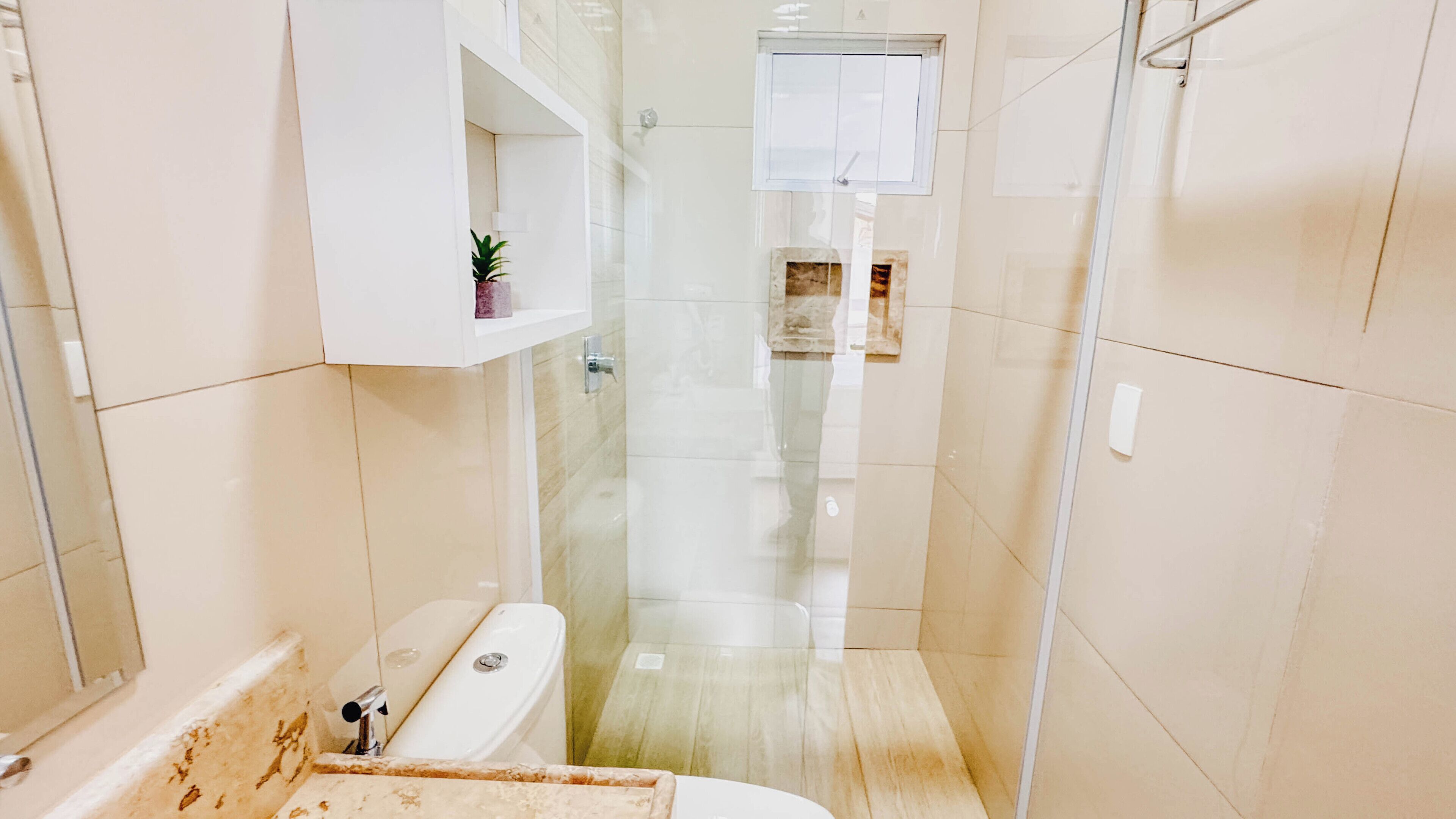 Ein modernes Badezimmer mit einer Duschkabine aus Glas, einer weißen Badewanne und einem kleinen Regal mit einer Pflanze.