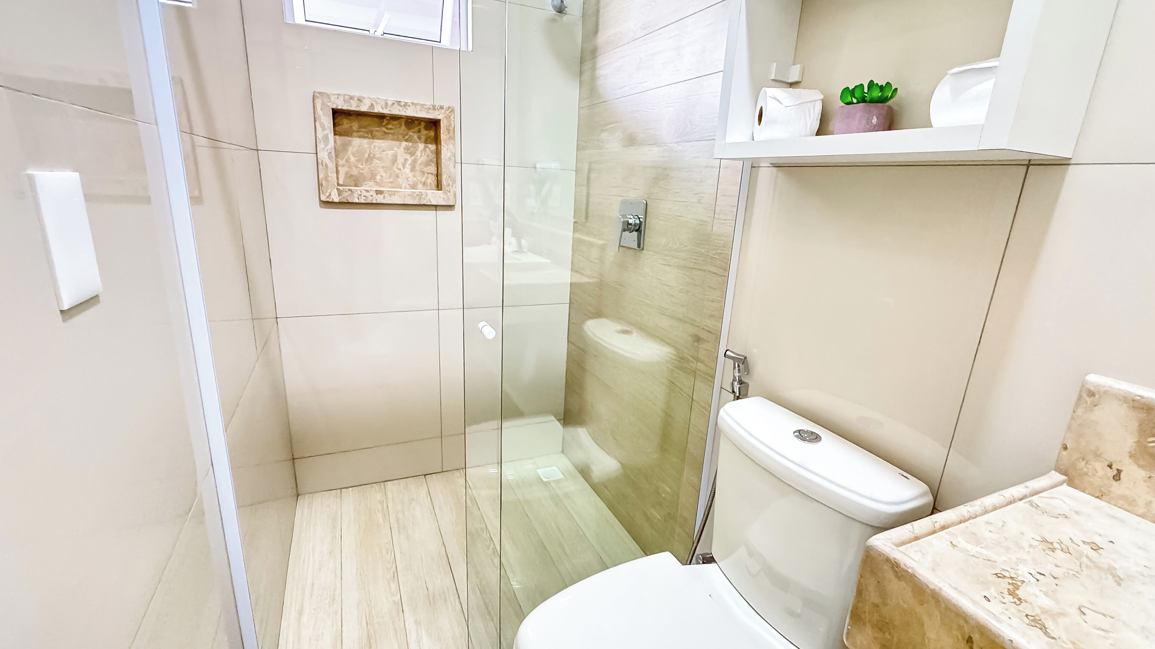 A modern bathroom with a glass-enclosed shower, a toilet, and a sink.