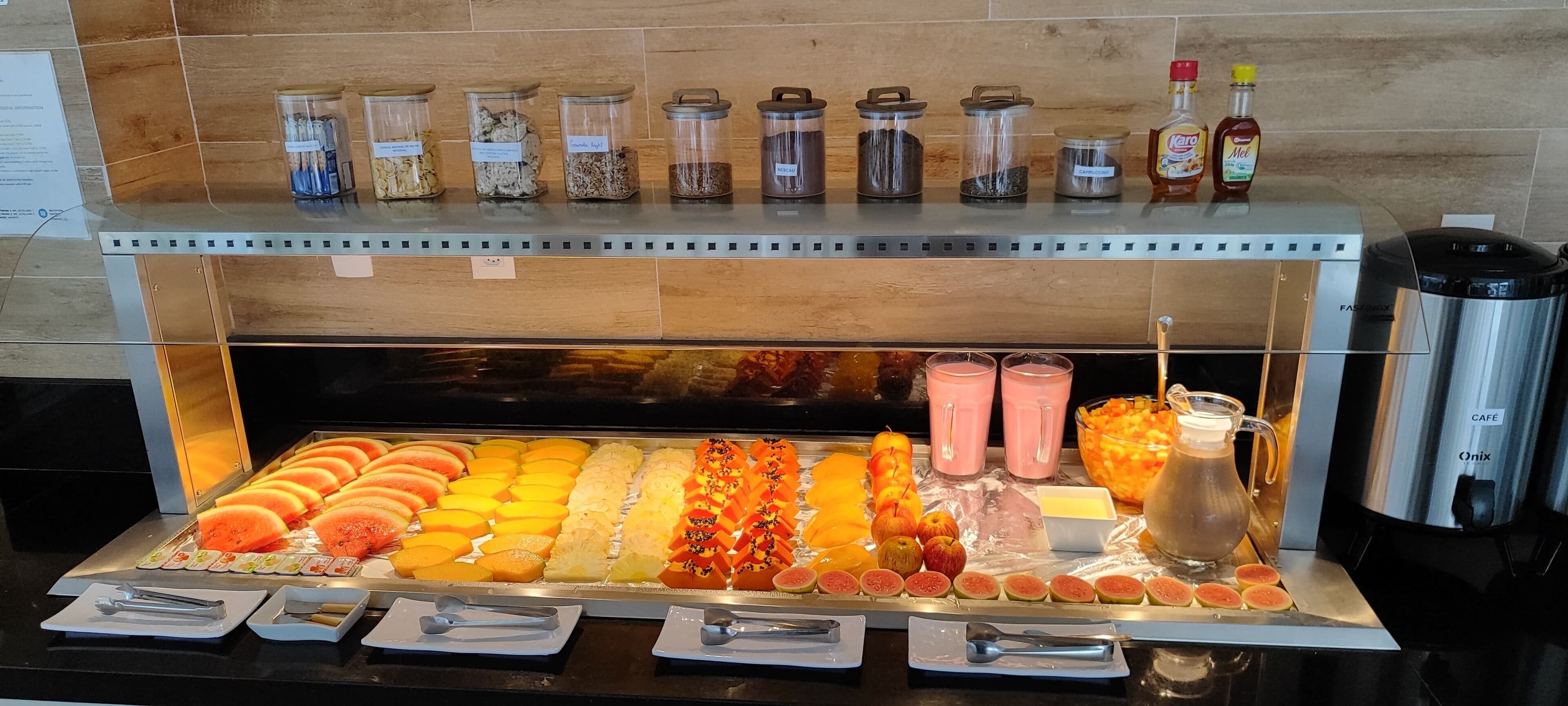 A buffet with various fruits, juices, and condiments.