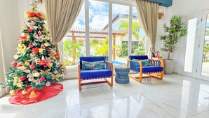 A modern living room with a Christmas tree, two blue armchairs, a red runner, and a view of the outdoors. - Pousada Diane (Trairi)