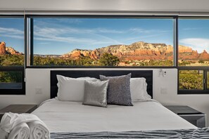 Ein Hotelzimmer mit einem großen Bett, zwei Nachttischen und Blick auf rote Felsformationen.