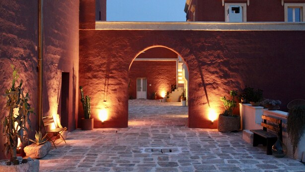 A courtyard with stone flooring, arched doorways, and potted plants. - Antica Masseria le Monache (Grottaglie)