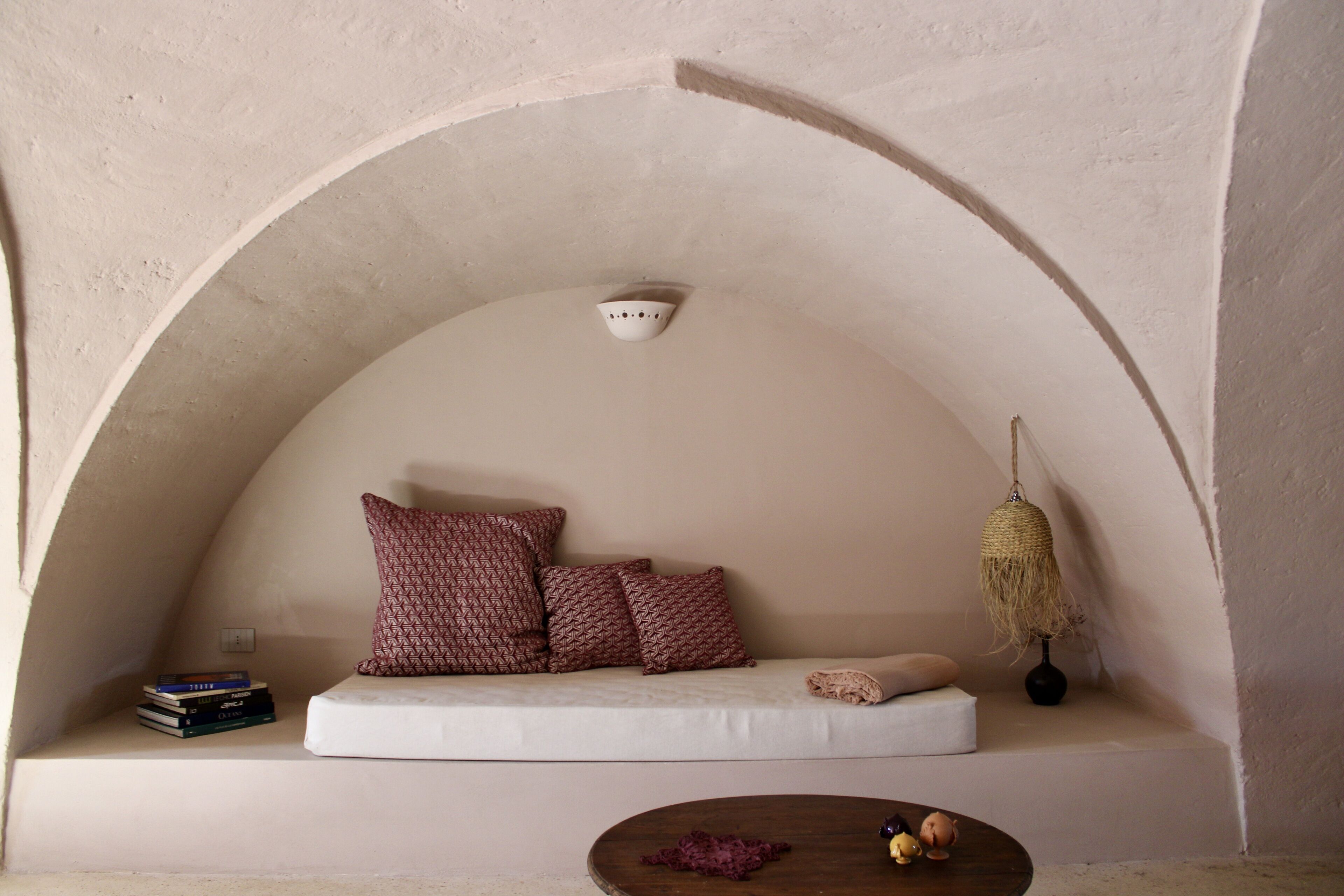 A cozy reading nook with a cushioned bench, a small table, and a hanging light fixture.