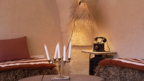 A cozy room with a stone ceiling, a table with candles, and a vintage telephone. - Antica Masseria le Monache (Grottaglie)