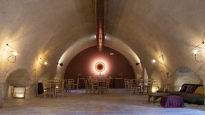 An interior with a high arched ceiling, a central round light fixture, and a dining area with chairs and tables. - Antica Masseria le Monache (Grottaglie)