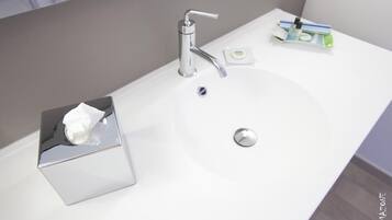 A modern bathroom with a chrome faucet, a tissue box, and a soap dispenser on the sink.