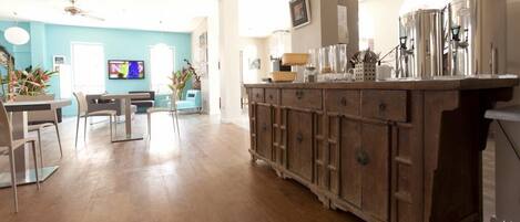 A spacious living room with a wooden cabinet, a television, and a dining area with chairs.