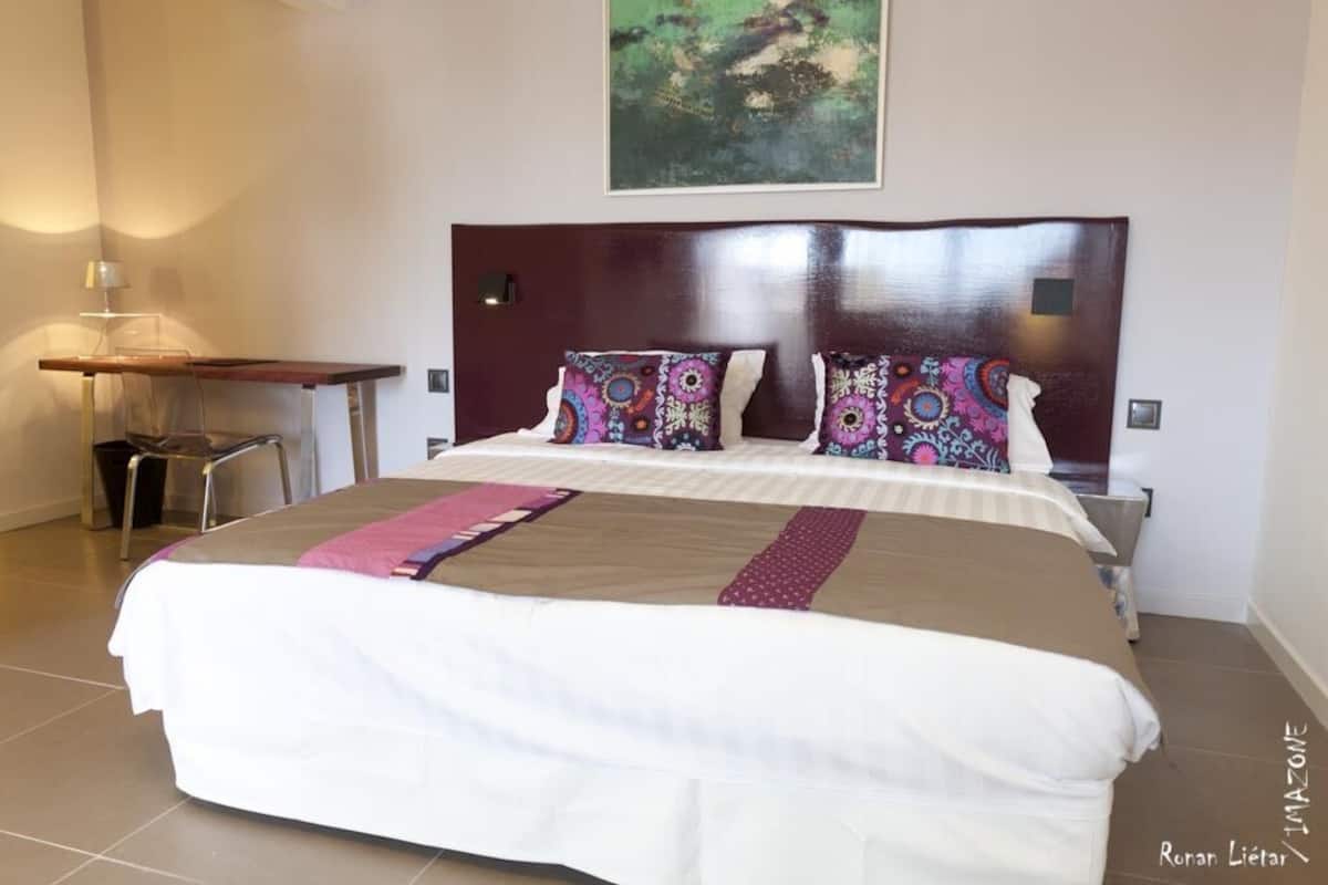 Ein Hotelzimmer mit einem großen Bett, einem hölzernen Kopfteil und einem Gemälde an der Wand.