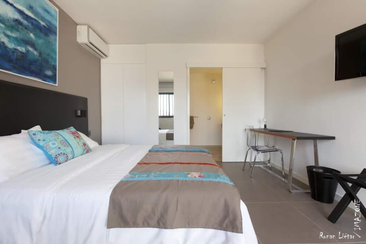 Ein modernes Hotelzimmer mit einem großen Bett, einem Schreibtisch und einem Fernseher.