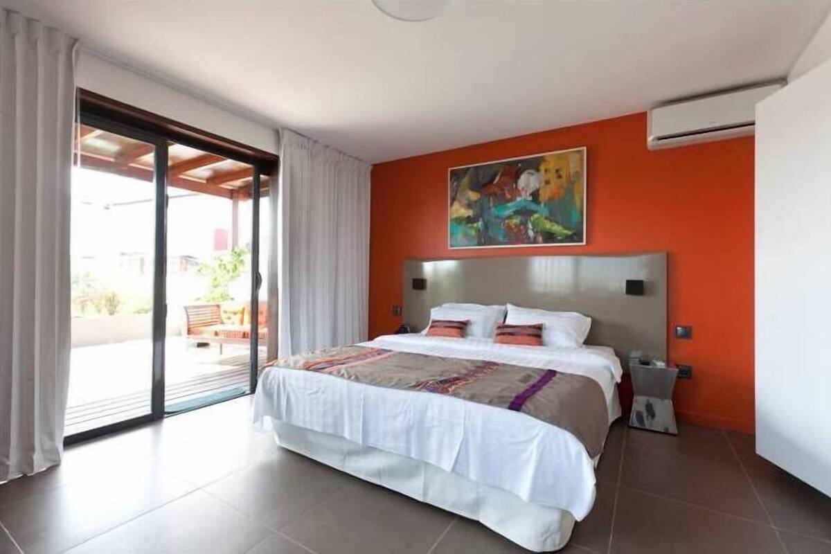Ein Hotelzimmer mit einem großen Bett, einem Gemälde an der Wand und einer Schiebetür nach draußen.