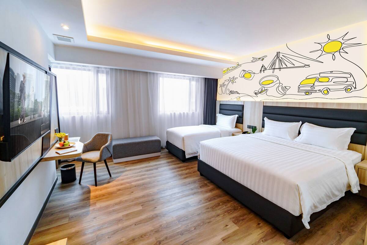 A hotel room with two beds, a desk, a chair, and a TV.