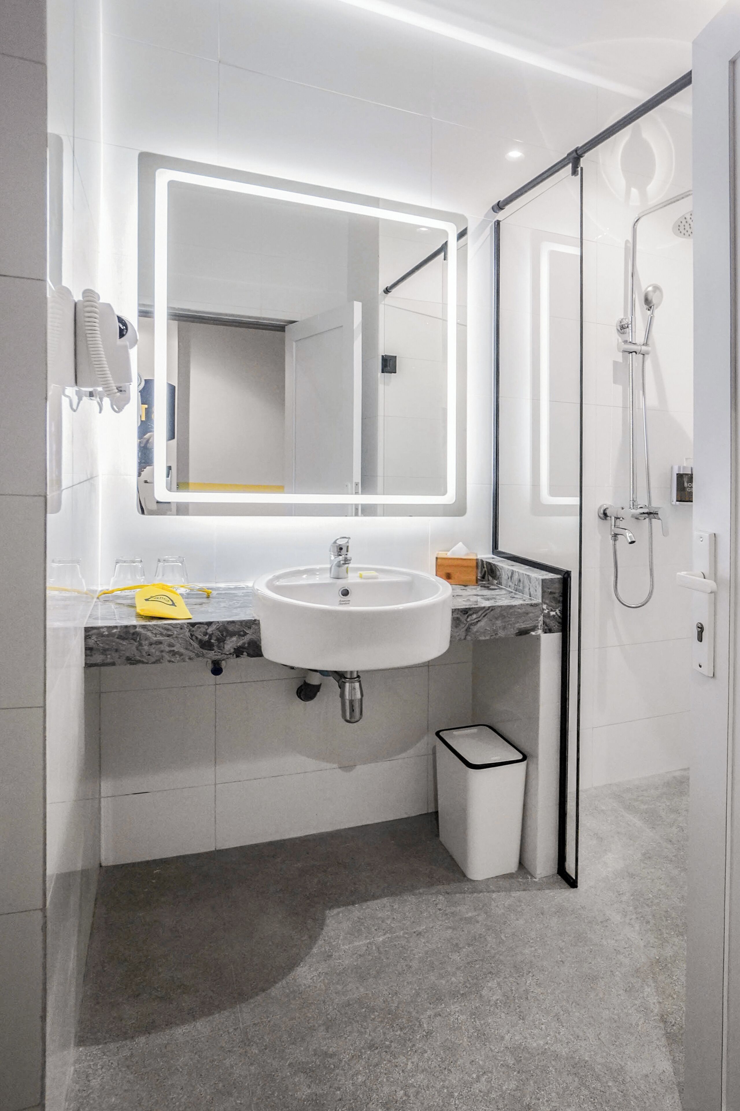A modern bathroom with a large mirror, white sink, and a glass-enclosed shower.