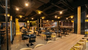 A spacious restaurant with multiple dining tables and chairs, modern pendant lighting, and a bar area. - YELLO Hotel Harbour Bay Batam (Batam)