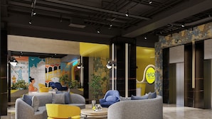 A modern lobby with a round seating area, a yellow accent chair, and a mural of a cityscape. - YELLO Hotel Harbour Bay Batam (Batam)