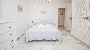 Un dormitorio con cama, mesitas de noche, armario y puerta.