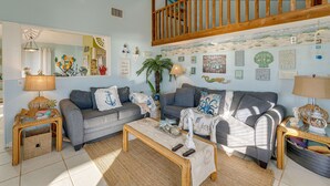 Ein gemütliches Wohnzimmer mit zwei grauen Sofas, einem Holztisch und einer Treppe mit Holzwangen.