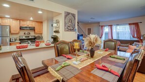 A dining area with a wooden table set for four, surrounded by chairs. A kitchen is visible in the background with wooden cabinets and modern appliances. - Lovely Concord Townhome Retreat w/ Community Pool! (Concord)