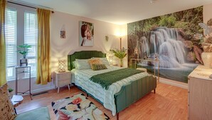 A bedroom with a bed, a nightstand, a lamp, a plant, and a large wall mural of a waterfall. - Lovely Concord Townhome Retreat w/ Community Pool! (Concord)